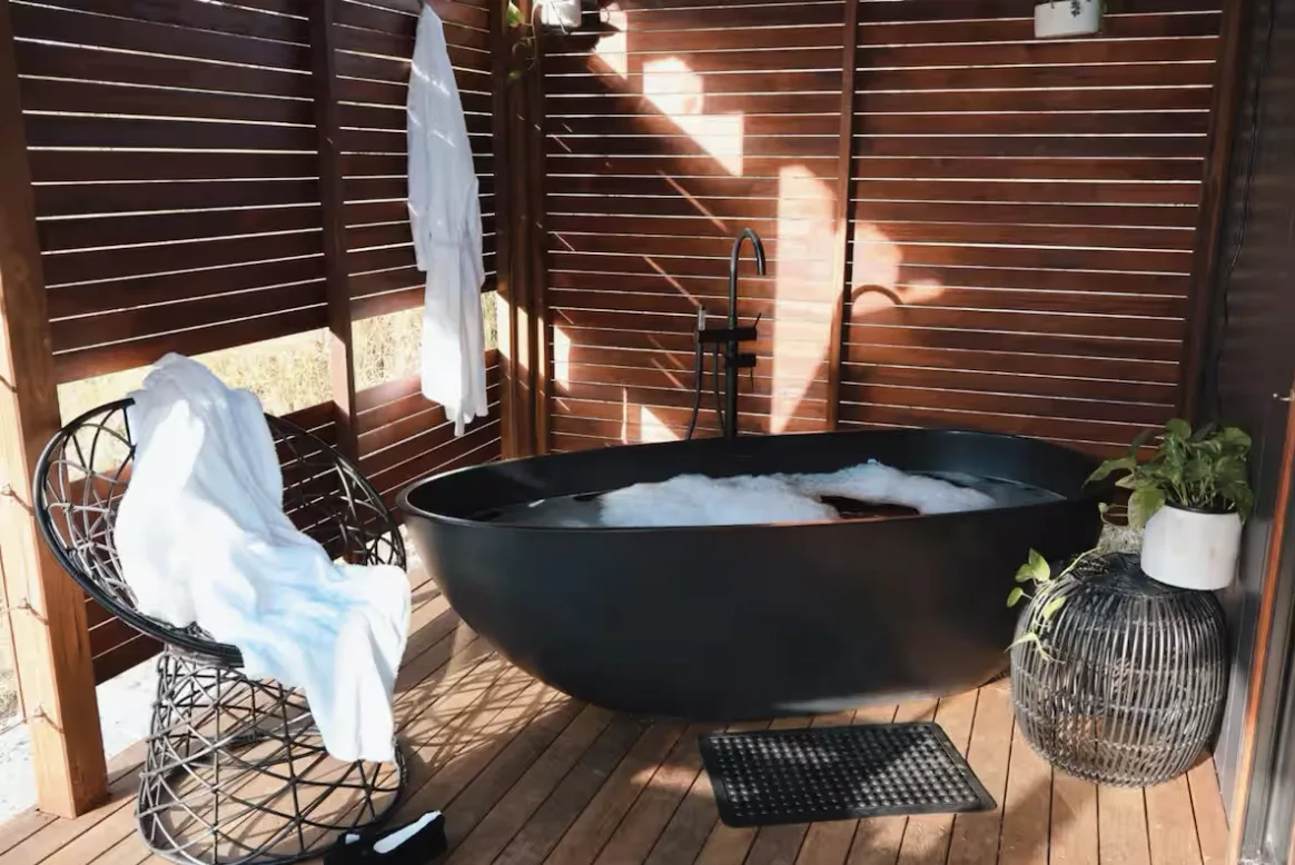 Freestanding black bath on the private timber deck