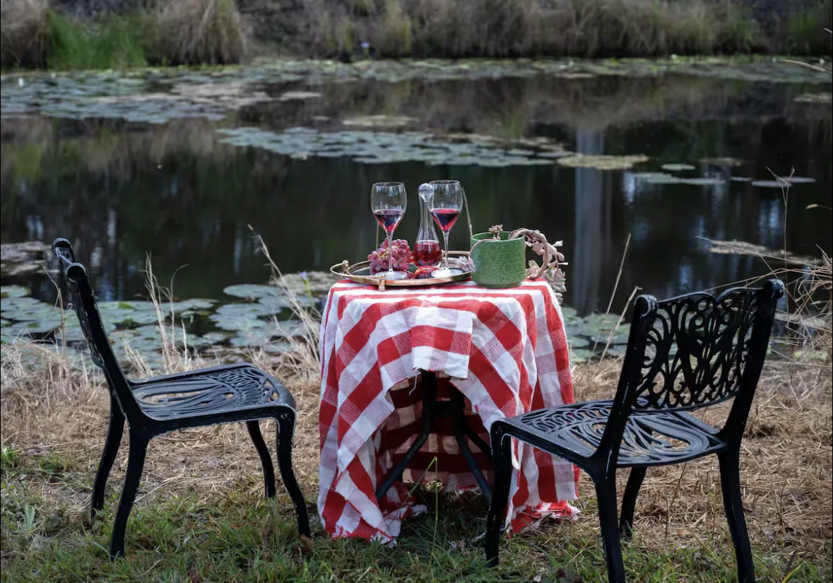 A gingham table set for two beside the lily-covered dam